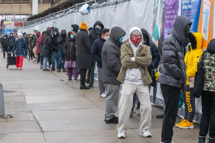 Dozens of masked New Yorkers wait on a line outside a COVID-19 testing site through a NYC Health + Hospitals site on Northern Boulevard in Queens earlier this month.
